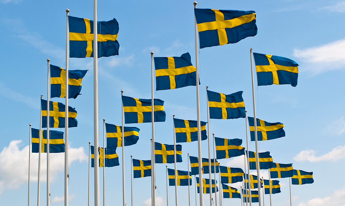 Svenska flaggor mot en blå himmel. Foto.