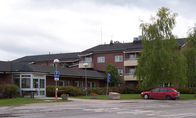 Alttext: matfors servicehus, rött tegelhus med grönytor runt. Fotograf: Socialtjänsten, Sundsvalls kommun Bildtext: -
