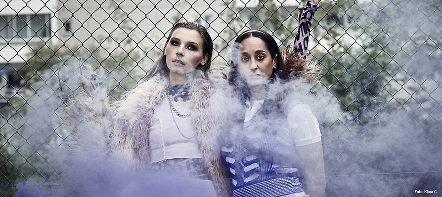 Två unga tjejer bakom ett moln av rök. 