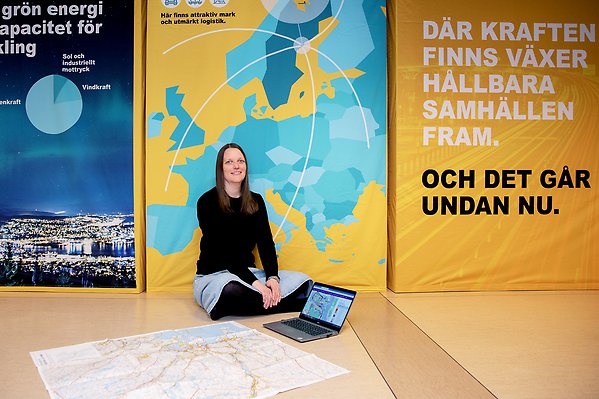 En kvinna sitter på golvet med en stor karta och en dator som visar kommunens översiktsplan 