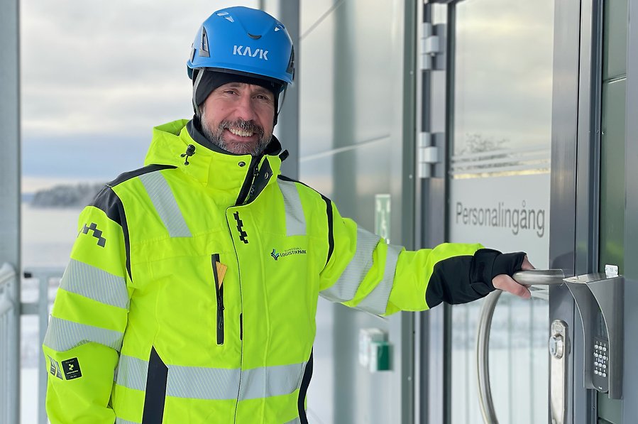 Byggledare Thomas Jönsson iklädd gul varseljacka och en blå hjälm på väg
in i en terminalbyggnad på Sundsvall Logistikpark.