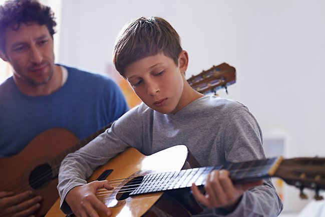 Pojke spelar gitarr. Foto.