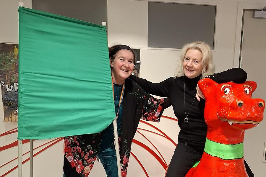 De två personerna Pia Fjällmo och Ingela Lindqvist står vid en valskärm och sitter på en drake i kommunens reception.