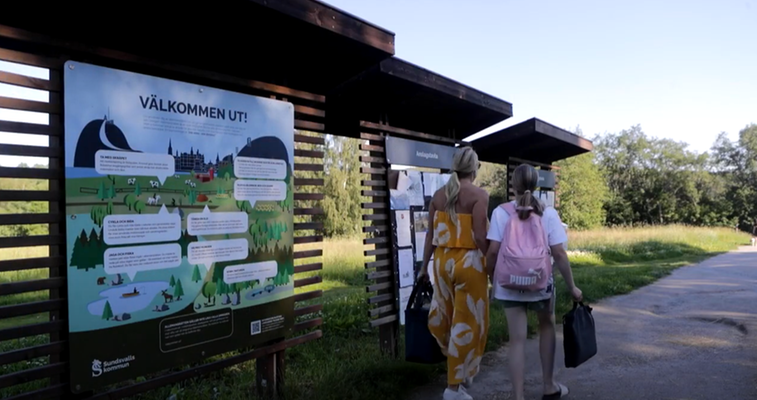 Två personer framför informationstavlor i naturreservat.