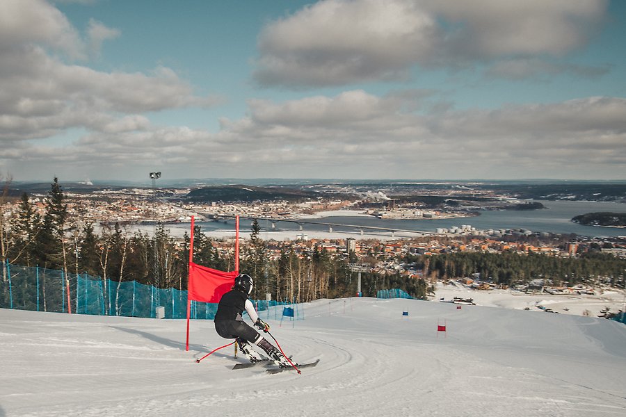 En person åker slalom ned för Södra Berget i centrala Sundsvall. Det är vitt och man ser ut över hela staden och havet.